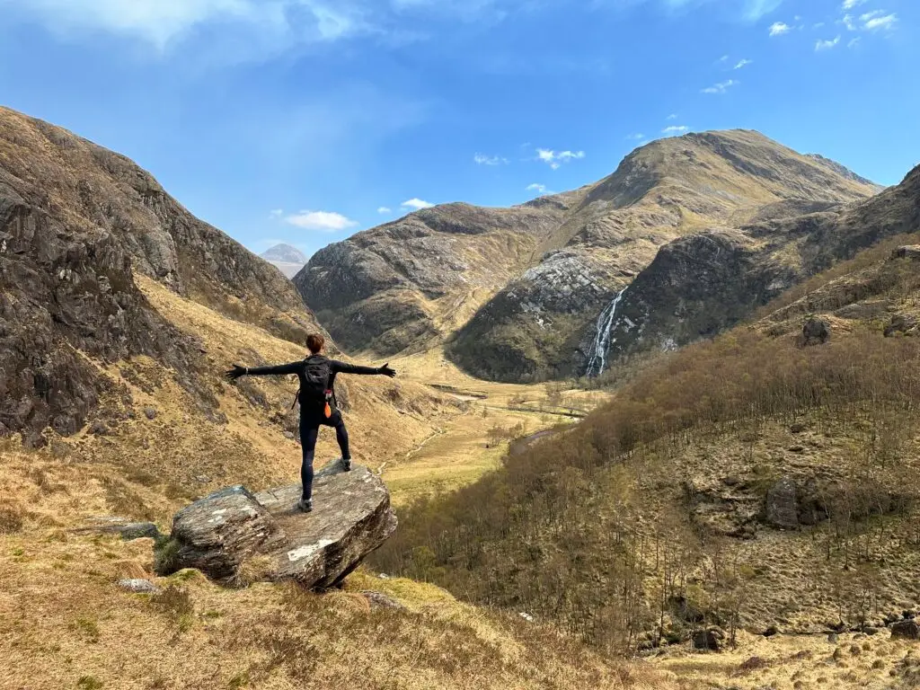 Terri on top of a rock looking out to the mountains. Our story begins in nature.