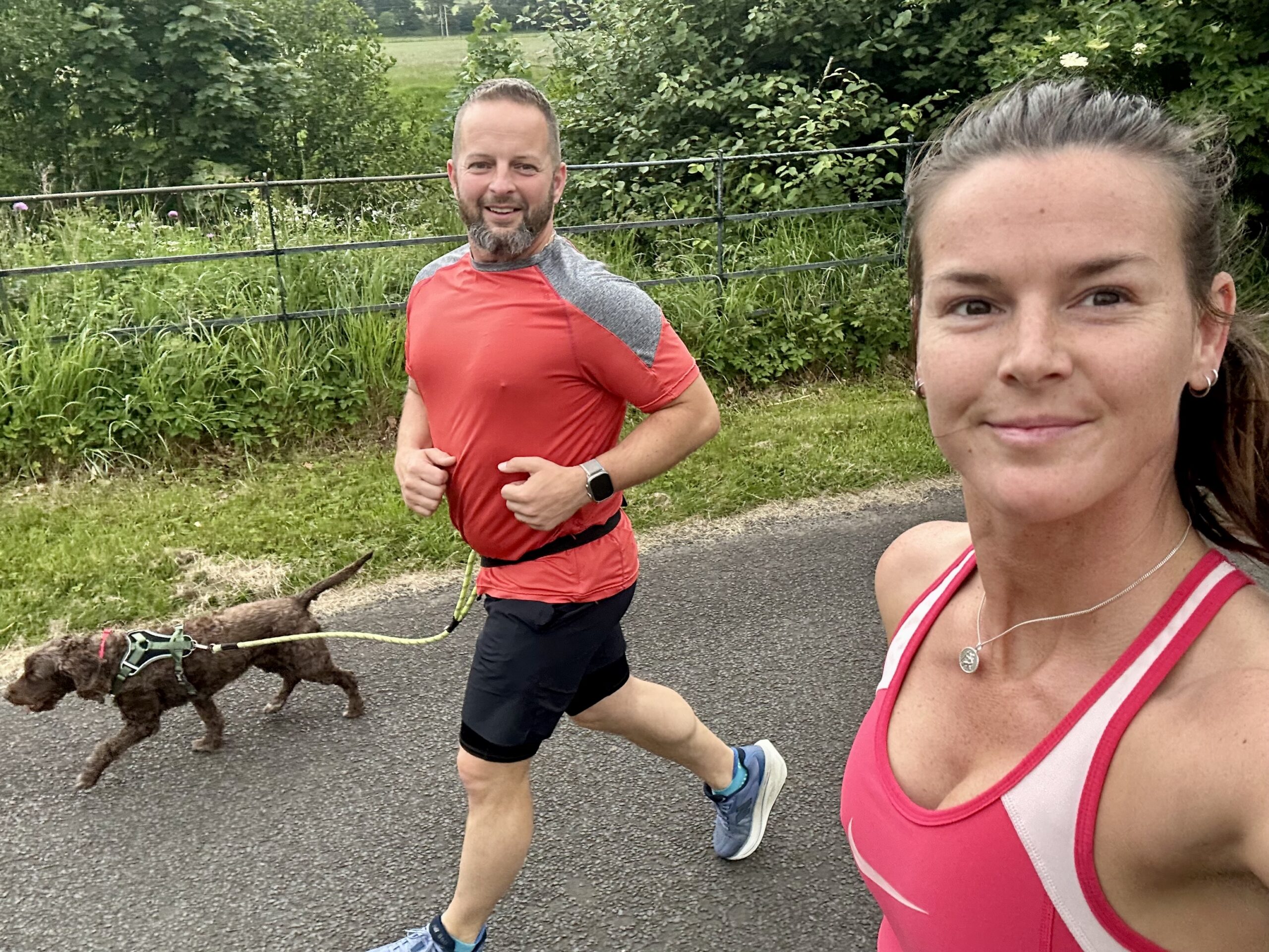 Stephen and Terri running together on a leafy lane, with their dog alongside them.