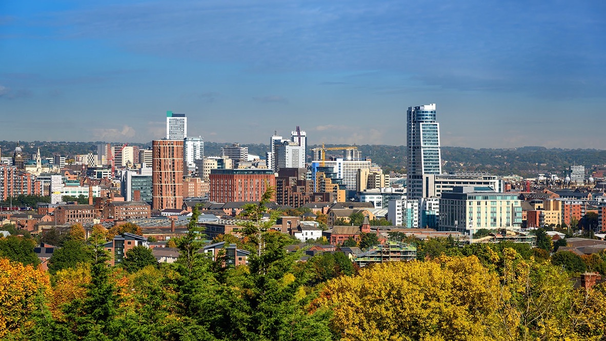 The Leeds skyline seen above trees in autumn colours.
